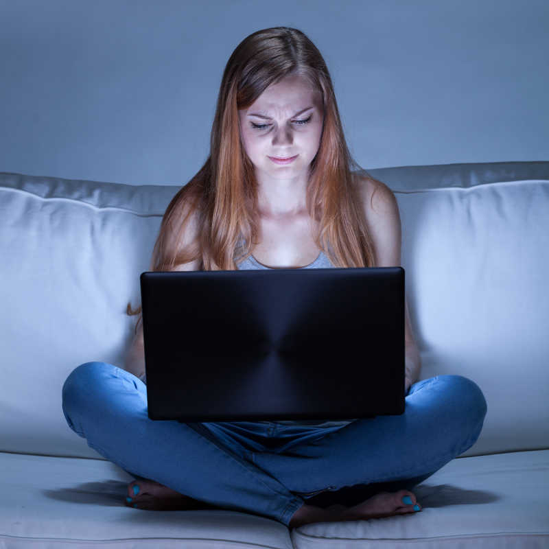 坐在沙发上玩笔记本电脑的美女