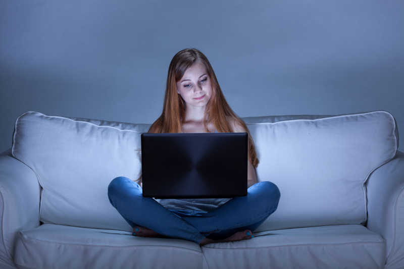 美女坐在沙发上玩电脑