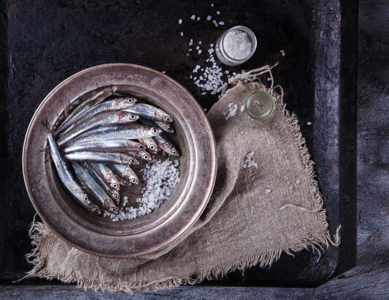 黑色桌上亚麻布和盘子里的鳀鱼