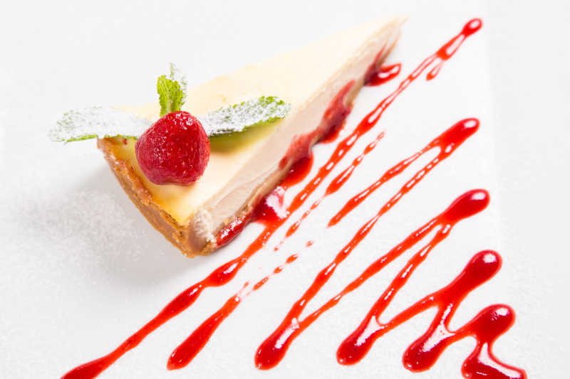 在白色背景在的新鲜奶油芝士蛋糕配草莓薄荷