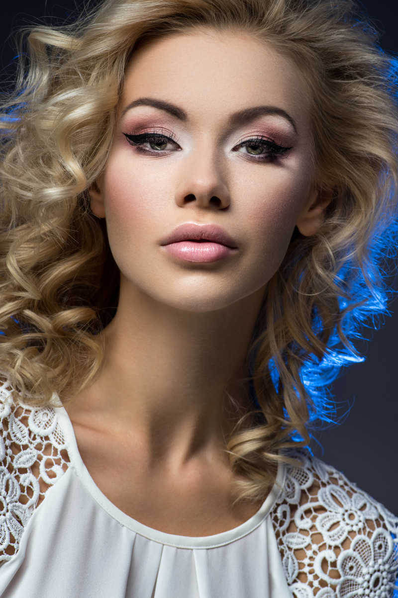 白色背景下穿着黑色胸罩的金发美女特写镜头