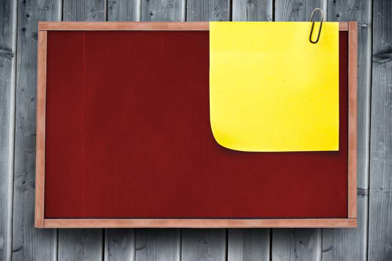 夹着黄色便签纸的红色黑板