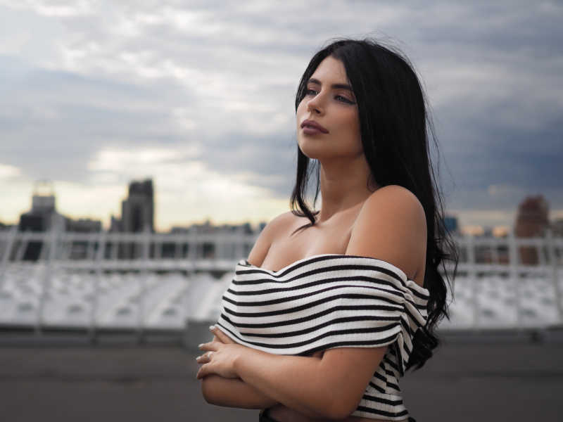 在模糊的城市背景下的性感的黑发美女