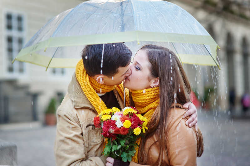 雨中伞下幸福亲吻的年轻情侣