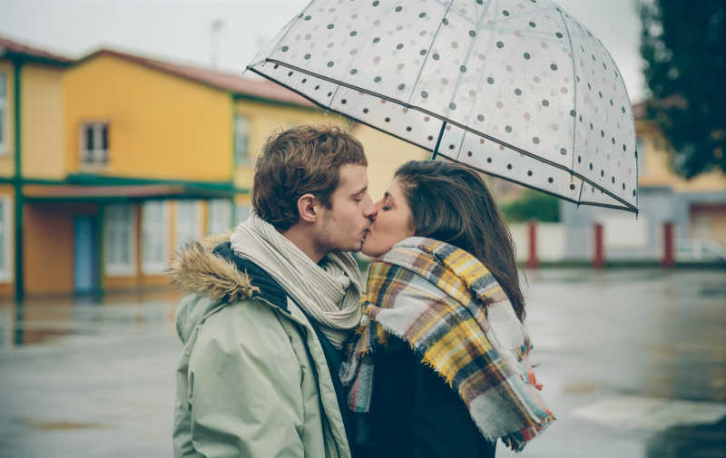 伞下年轻夫妇甜蜜亲吻