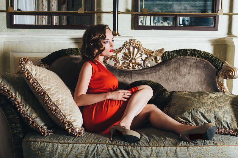 红色裙子复古发型的美女躺在沙发上