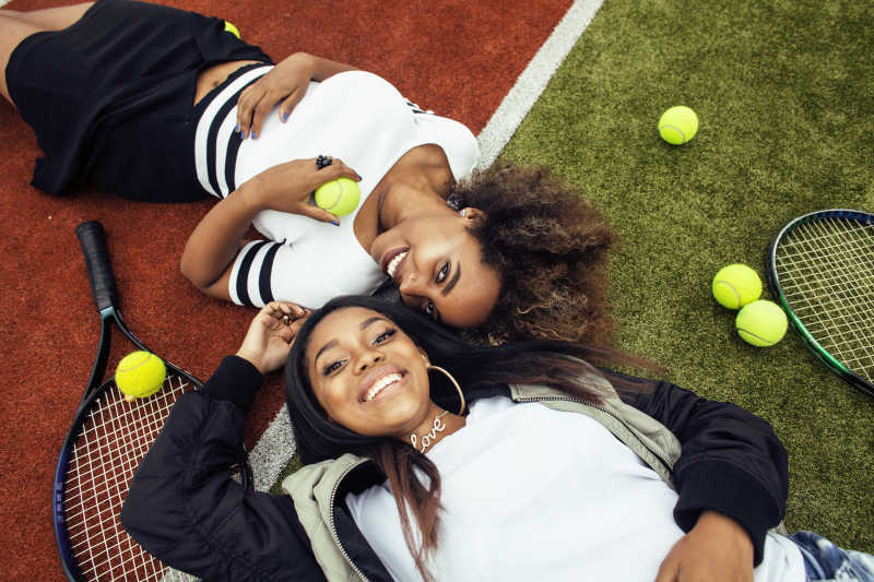 漂亮的躺在网球场上的年轻女孩