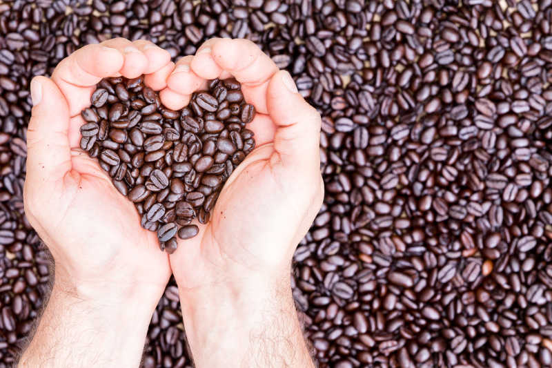双手捧着咖啡豆摆成的心型图案