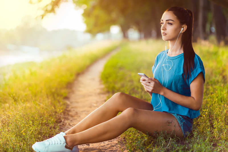 坐在河边听音乐的年轻女孩