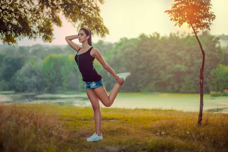 在户外戴着耳机健身的年轻女孩