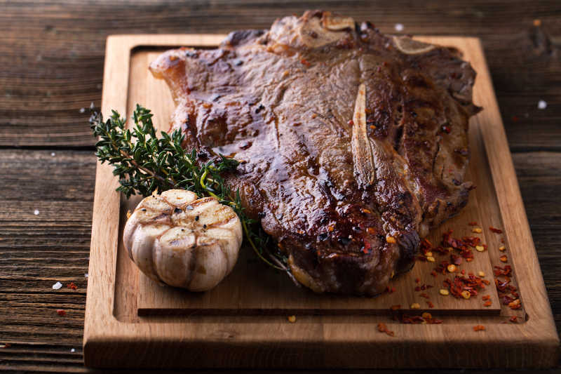 美味的放了香辛料的木制背景上的香烤牛排