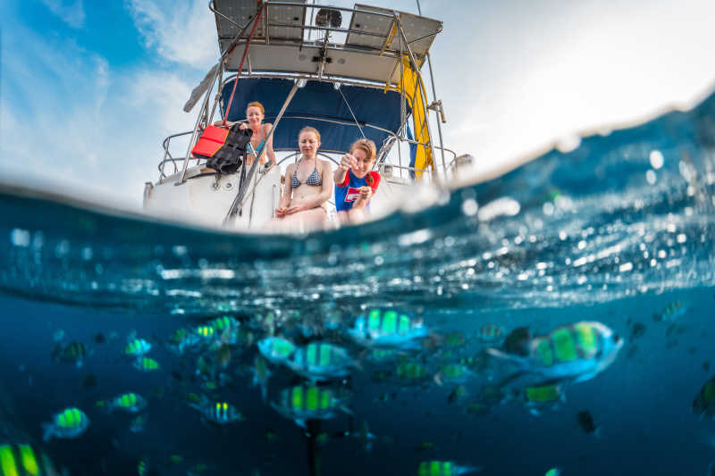 坐在游艇上喂鱼的三个年轻女子