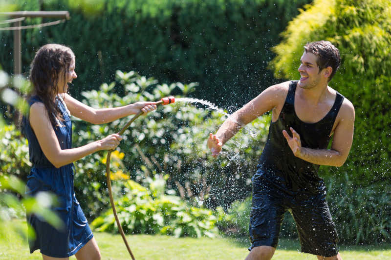 快乐的草地上玩水的年轻夫妇