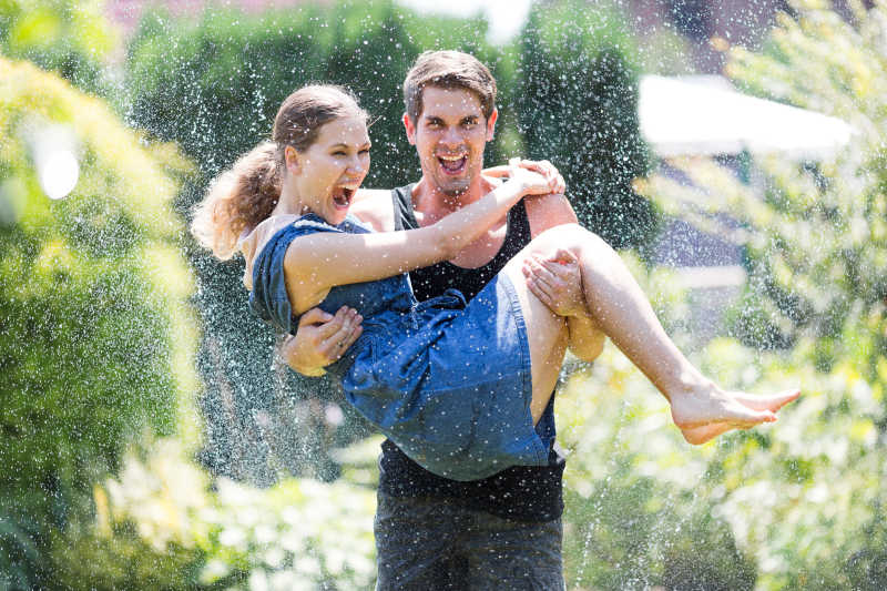 在草地上玩水的年轻夫妇