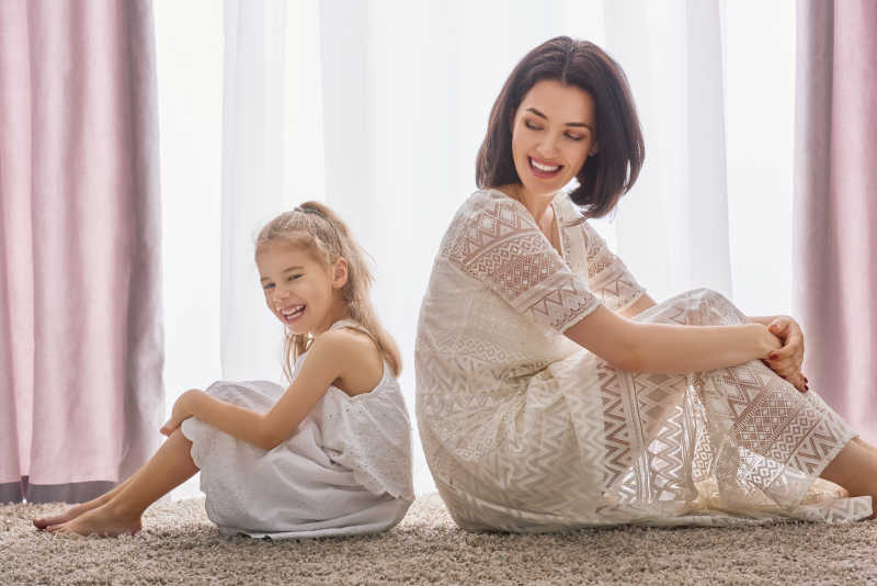 窗前背靠背的快乐幸福的母女