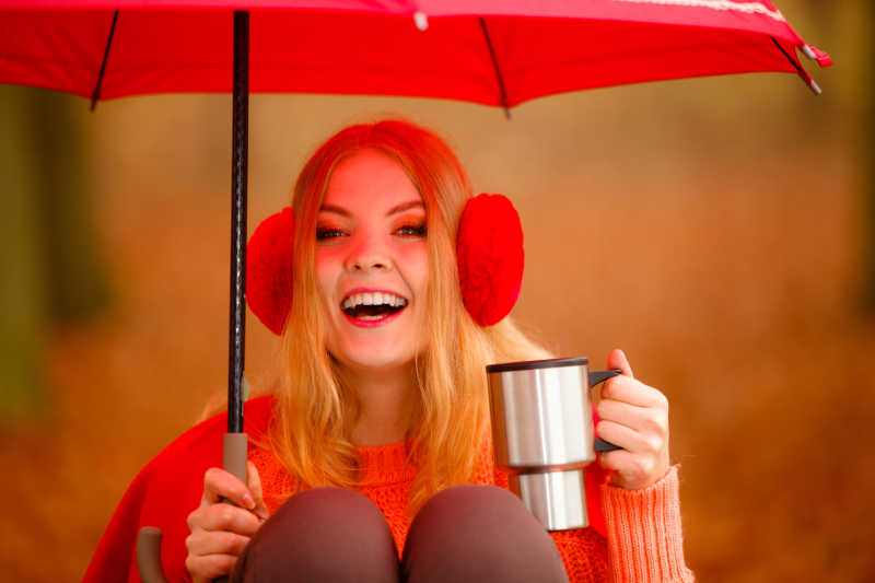 秋天公园里的女孩正在享受热饮