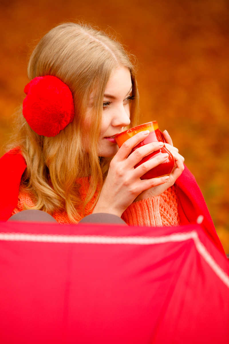 秋天公园里的女孩喝热饮