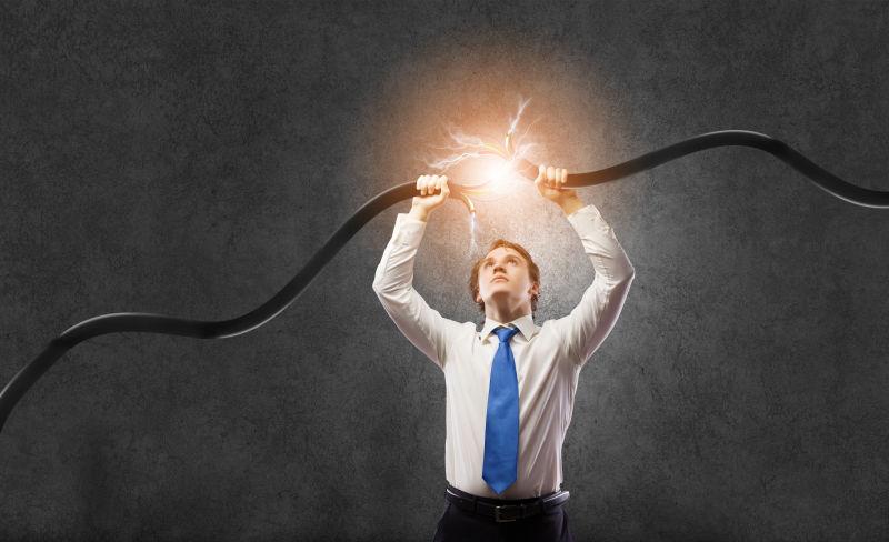 灰色背景下商人拿着断掉的电线