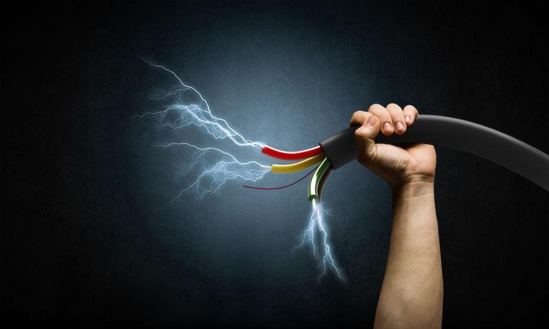 黑色背景下单手握住电线