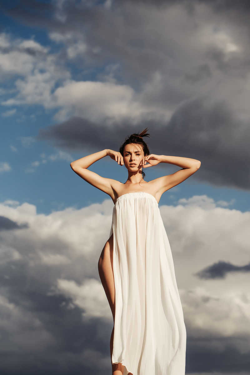 在昏暗的天空下穿着白色纱裙的性感美丽的女人