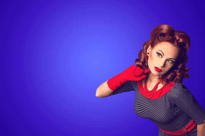 蓝色背景上穿复古服装的年轻红发女人