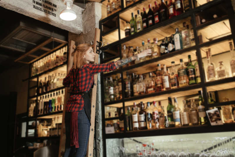 服务生从酒吧货架上拿出一瓶酒