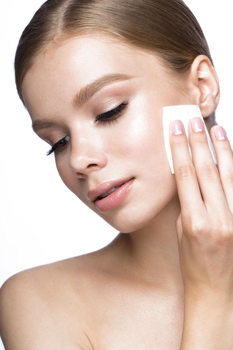 漂亮的年轻女孩用抹布擦拭化妆品