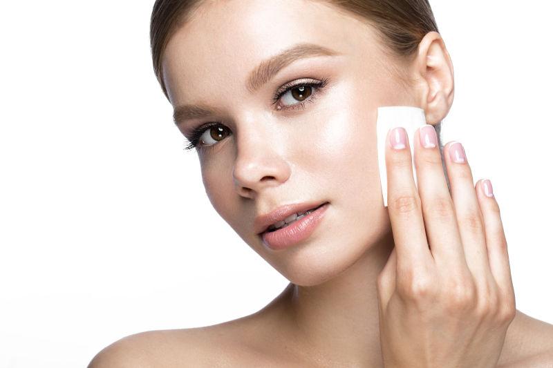 漂亮的年轻女孩用湿巾擦拭化妆品