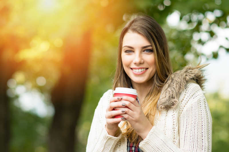 秋天公园里的美女捧着咖啡