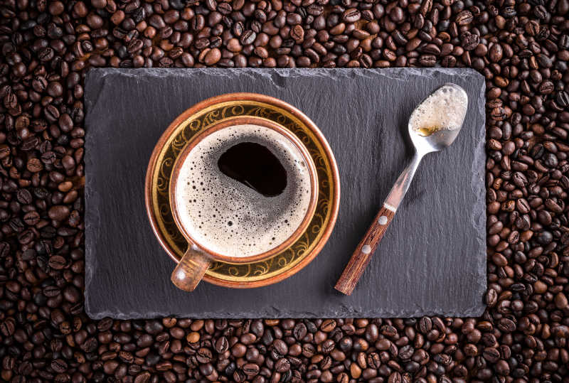 美味的咖啡和勺子放在咖啡豆的上面俯视摄影