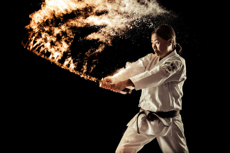 黑背景中日本女性拿着带火的刀