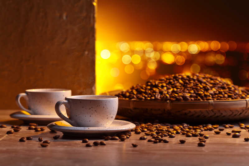 金色阳光下的棕色咖啡豆和两杯咖啡