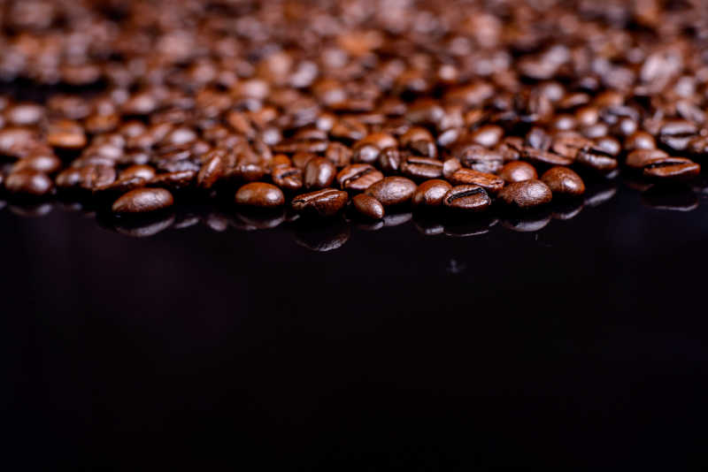 许多的咖啡豆在黑色玻璃桌上
