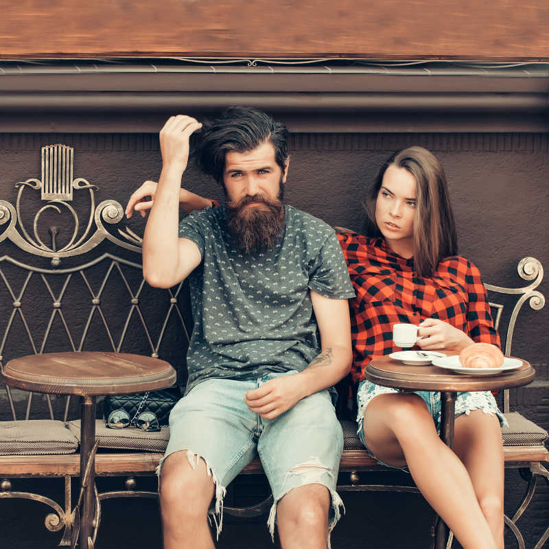 漂亮的女孩和长胡子帅哥坐在老式咖啡馆的沙发上