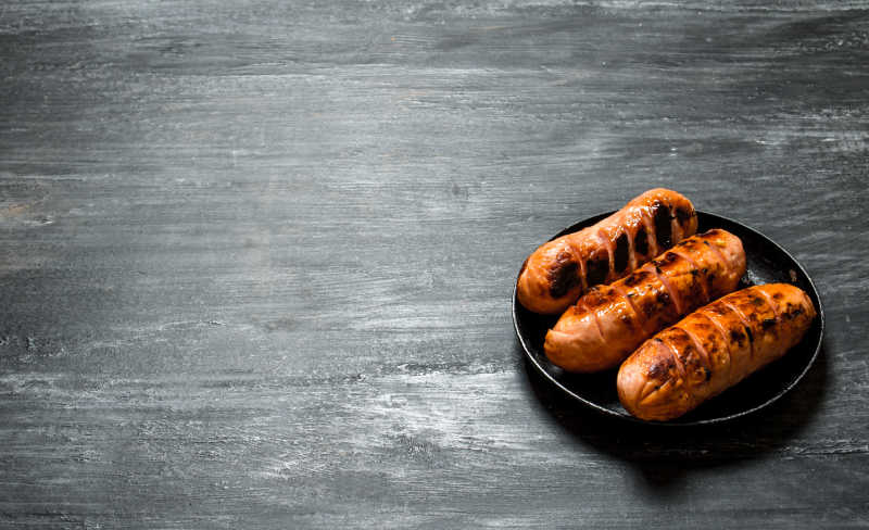 黑色盘子里的三根烤肠