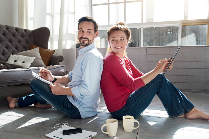 中年夫妇坐在靠近窗户的地板上微笑