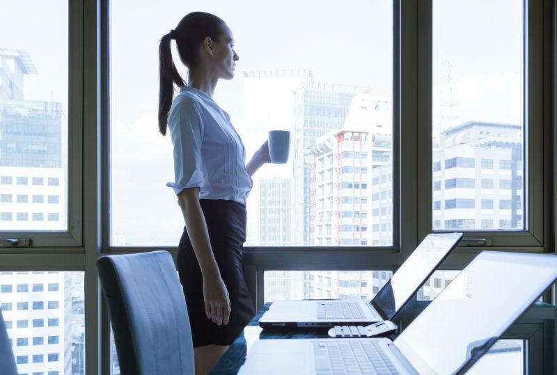 端着水杯看着窗外的办公女性