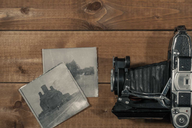 木桌上的黑色复古相机和照片