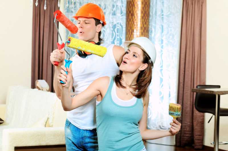 拿着漆辊开心嬉戏的夫妇