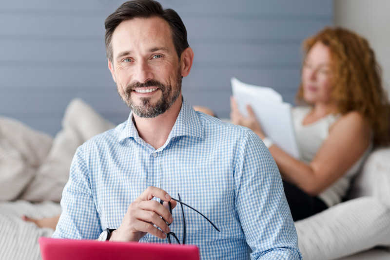 女人背景下带笔记本电脑的微笑男人