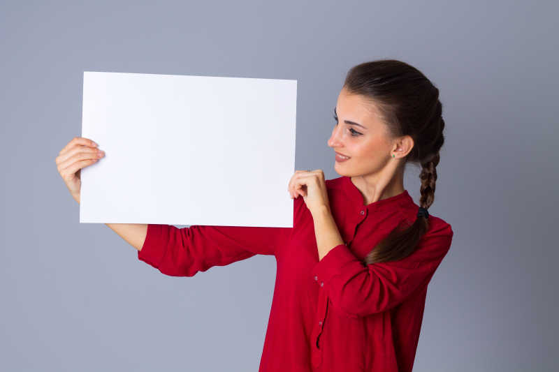 灰色背景下女人拿着一张白纸