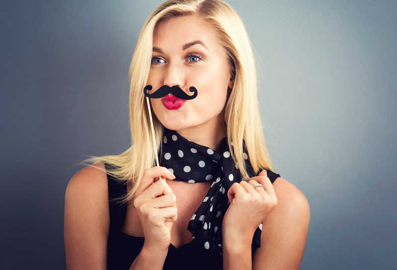 灰色背景下拿纸党棍的金发美女