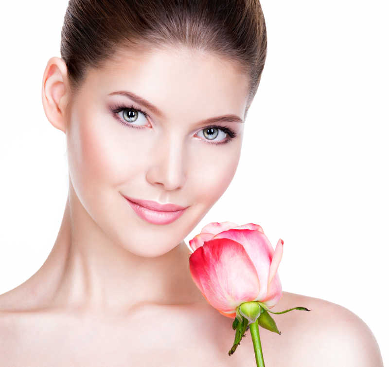 白色背景下闻着玫瑰花香味的年轻性感的美女