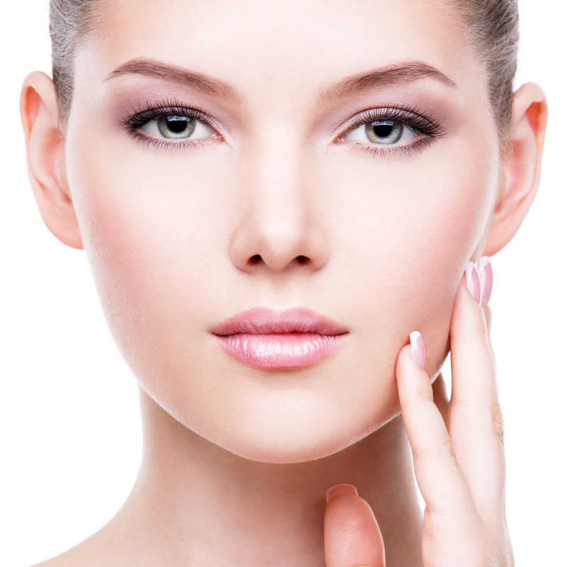 白色背景下抚摸自己面部的年轻女人