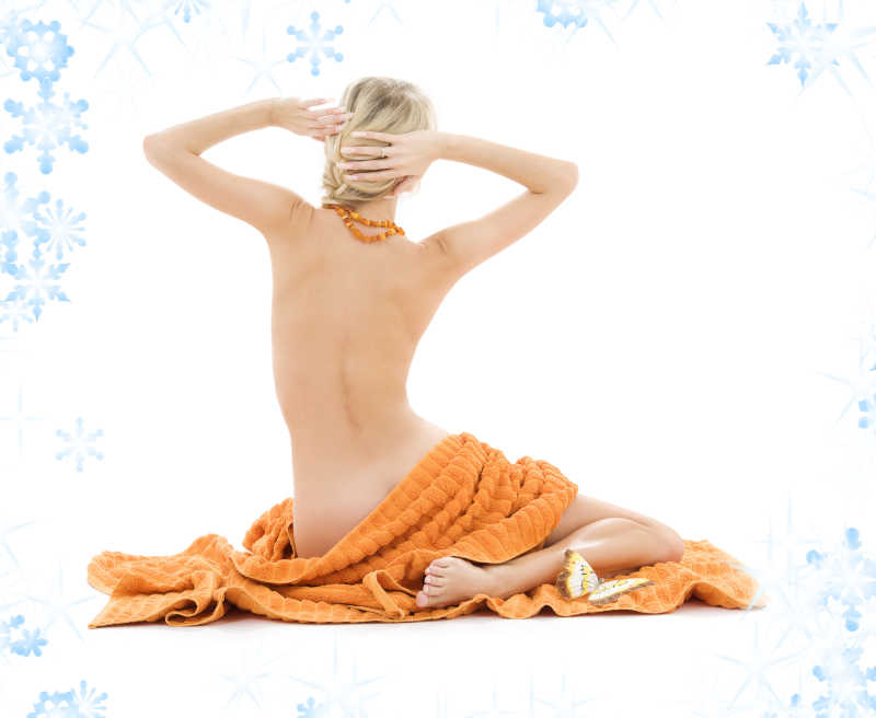 做水疗的年轻女人在橙色毛巾上