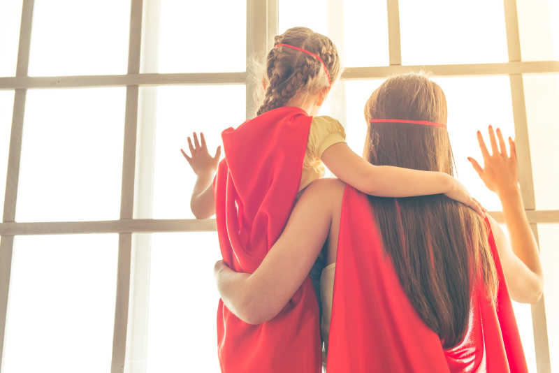 站在窗户旁打扮成超级英雄的母女