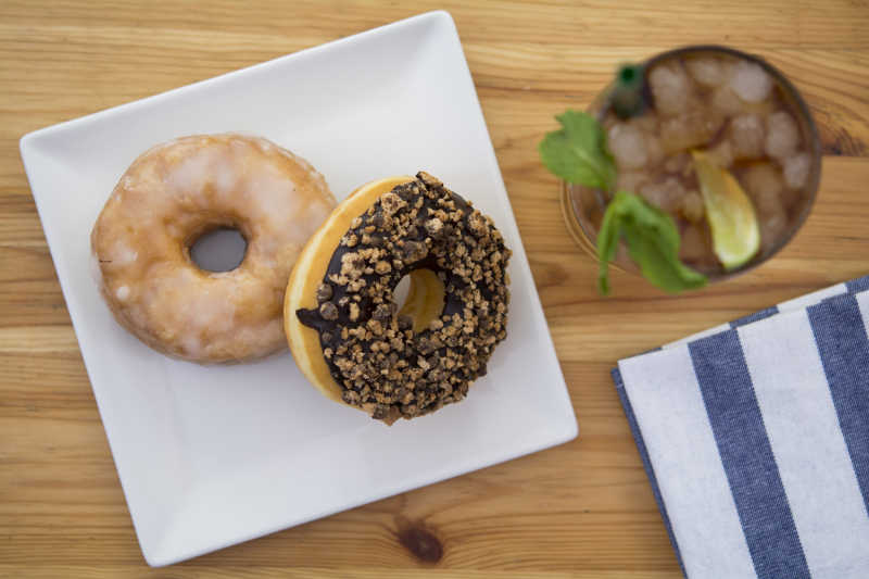 木桌上白色盘子里的甜甜圈