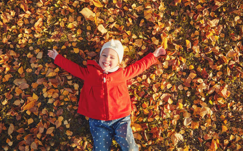 躺着金黄树叶上大笑的女孩
