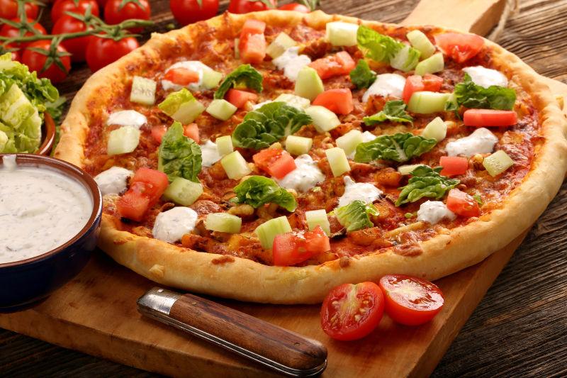 木制背景下的鸡肉和蒜酱自制比萨饼