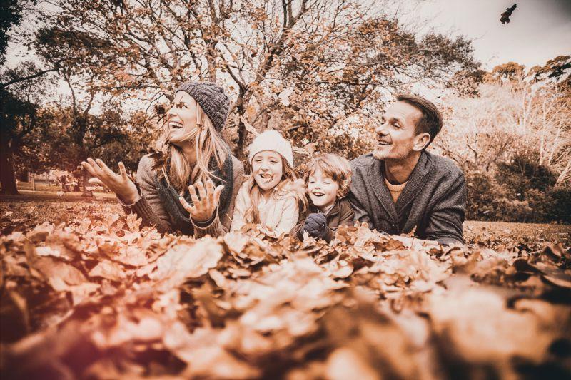 秋季落叶背景下玩耍的快乐一家人